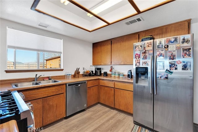 kitchen with visible vents, brown cabinetry, appliances with stainless steel finishes, light countertops, and a sink