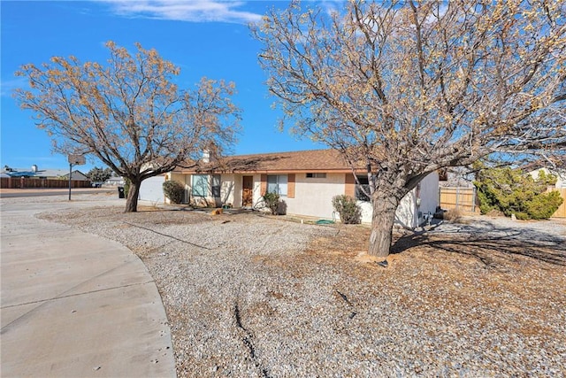 ranch-style home featuring fence and stucco siding