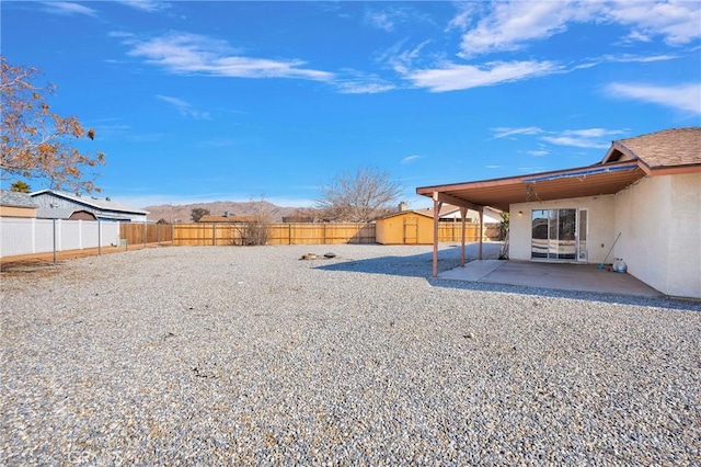 view of yard with a patio, a shed, an outdoor structure, and a fenced backyard