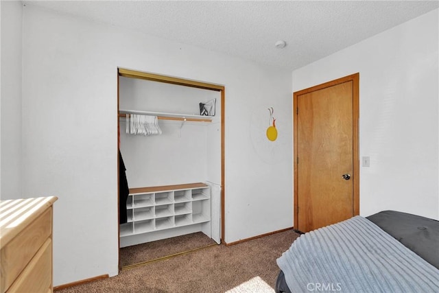 bedroom featuring a closet, light colored carpet, a textured ceiling, and baseboards