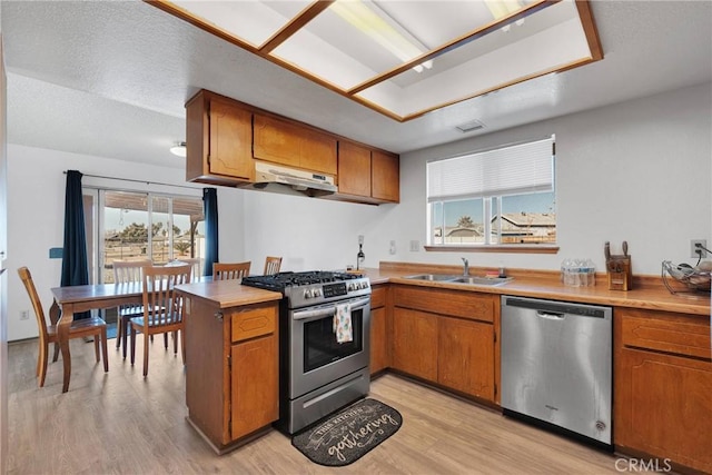 kitchen featuring stainless steel appliances, brown cabinetry, light countertops, and a sink