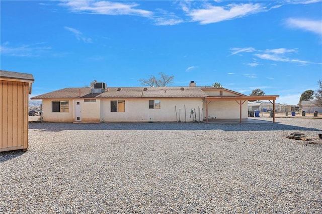 rear view of property featuring central AC unit, a patio area, fence, and stucco siding