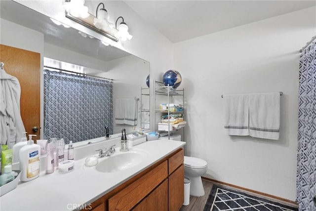 bathroom with curtained shower, toilet, wood finished floors, vanity, and baseboards