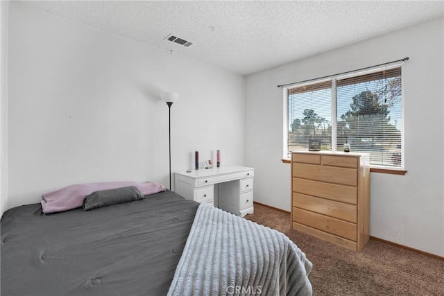 bedroom with baseboards, visible vents, dark carpet, and a textured ceiling