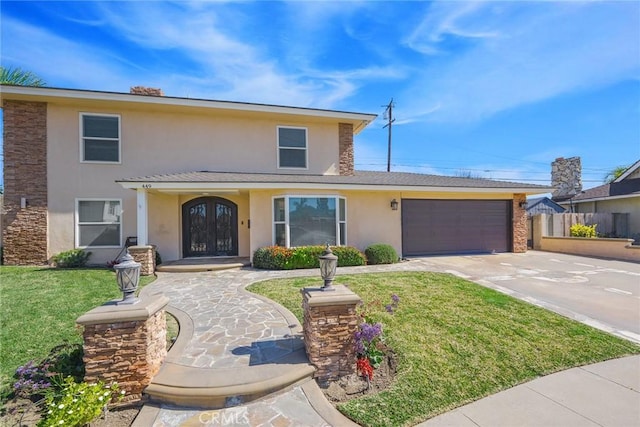 traditional home featuring a garage, driveway, french doors, stucco siding, and a front lawn