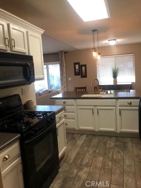 kitchen with dark wood-style floors, pendant lighting, dark countertops, a sink, and black appliances