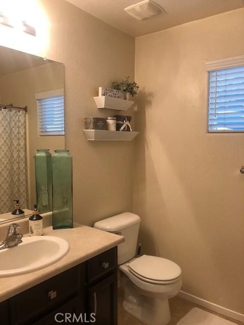 bathroom with visible vents, baseboards, toilet, tile patterned floors, and vanity