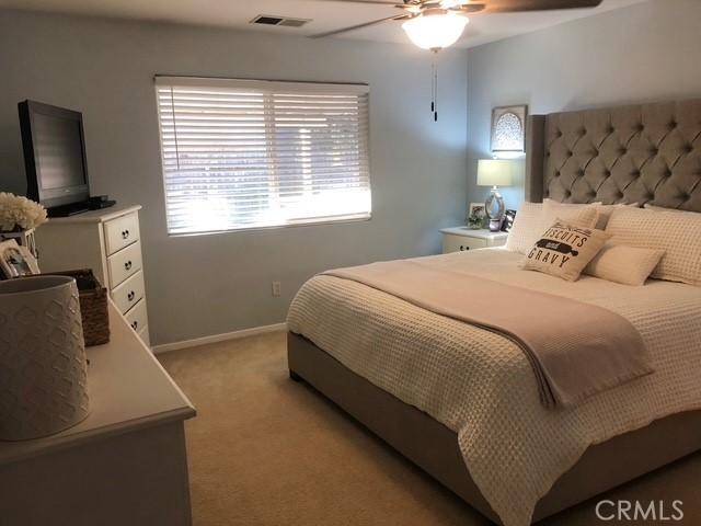 bedroom with a ceiling fan, light colored carpet, visible vents, and baseboards