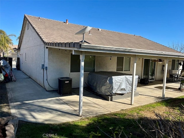 rear view of property featuring a tiled roof, central air condition unit, a patio, and stucco siding