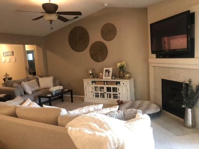 living area featuring baseboards, light colored carpet, ceiling fan, vaulted ceiling, and a fireplace