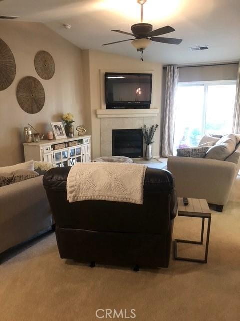 living area with visible vents, a tiled fireplace, light colored carpet, lofted ceiling, and ceiling fan