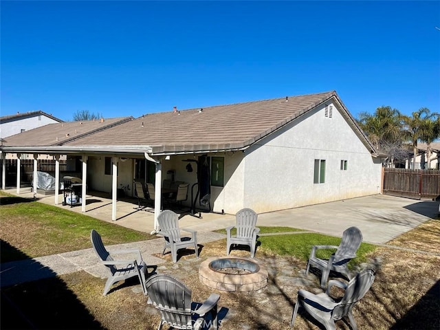 back of property featuring a fire pit, a patio, fence, and stucco siding