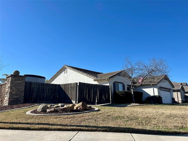 view of home's exterior with a garage, a yard, fence, and stucco siding