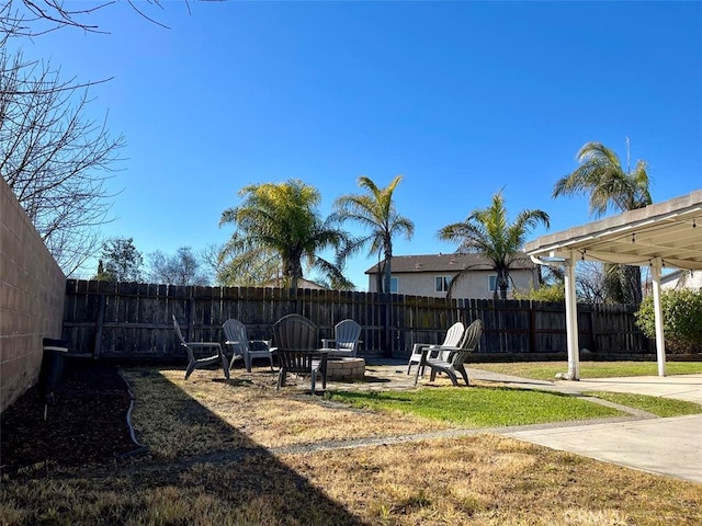 view of yard featuring a patio area, fence, and a fire pit