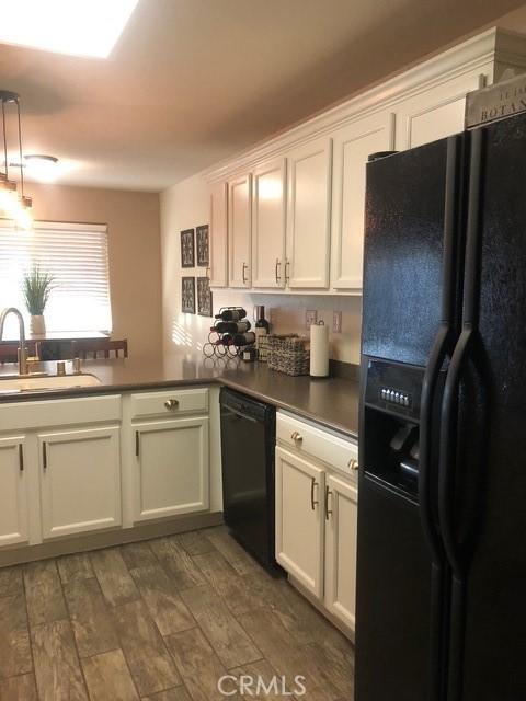 kitchen featuring dark countertops, black appliances, dark wood-style floors, and a sink