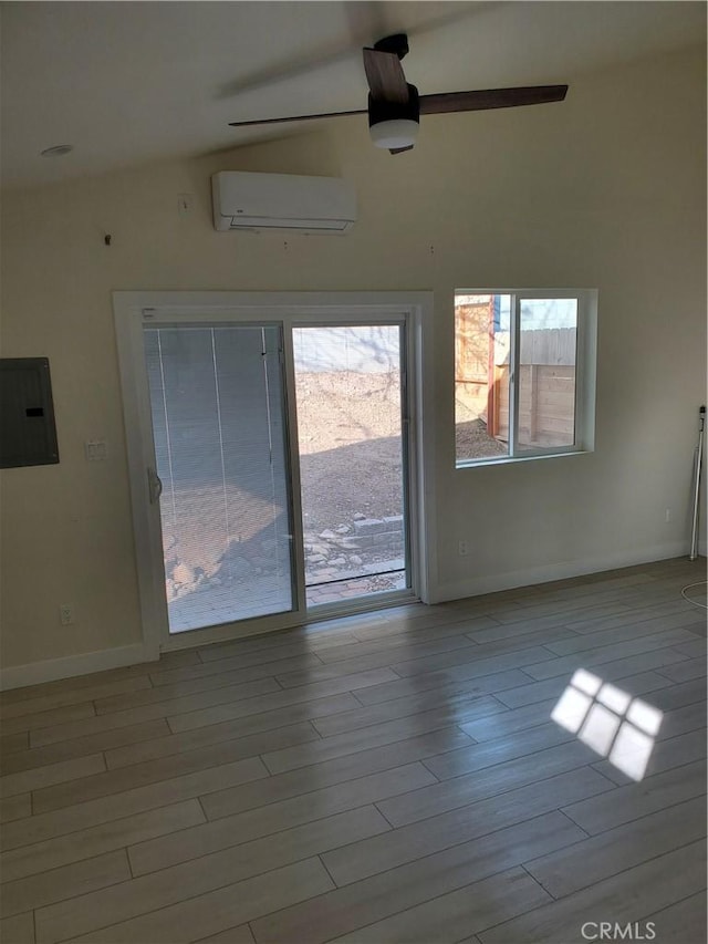 unfurnished room featuring a wall mounted air conditioner, wood finished floors, electric panel, and ceiling fan