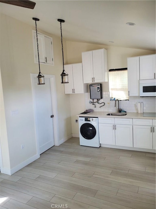 kitchen with white microwave, washer / clothes dryer, a sink, vaulted ceiling, and tasteful backsplash