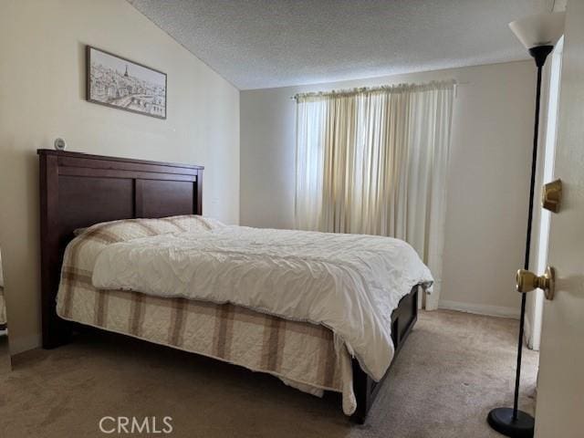 carpeted bedroom with vaulted ceiling and a textured ceiling