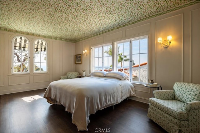 bedroom featuring dark wood finished floors and a decorative wall