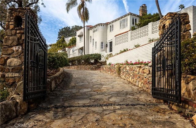 exterior space with dirt driveway, a gated entry, and a gate