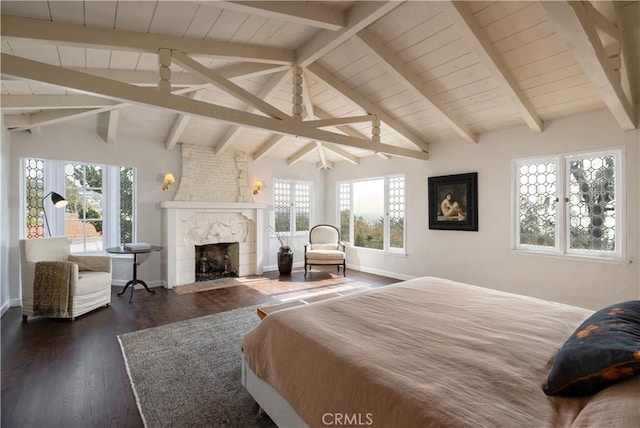 bedroom with lofted ceiling with beams, a large fireplace, dark wood finished floors, and baseboards