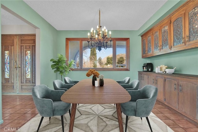 dining room with a chandelier, a textured ceiling, and light tile patterned flooring