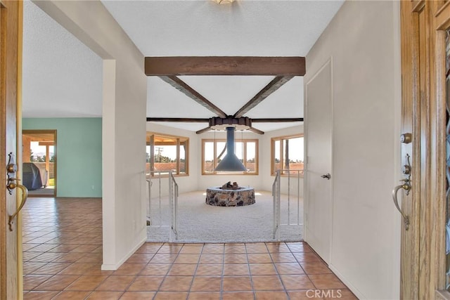 foyer entrance with tile patterned flooring, beamed ceiling, and a textured ceiling