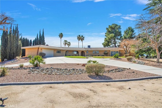 ranch-style house with a garage, driveway, and stucco siding