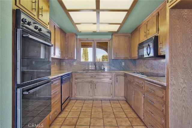 kitchen with black appliances, decorative backsplash, light countertops, and a sink