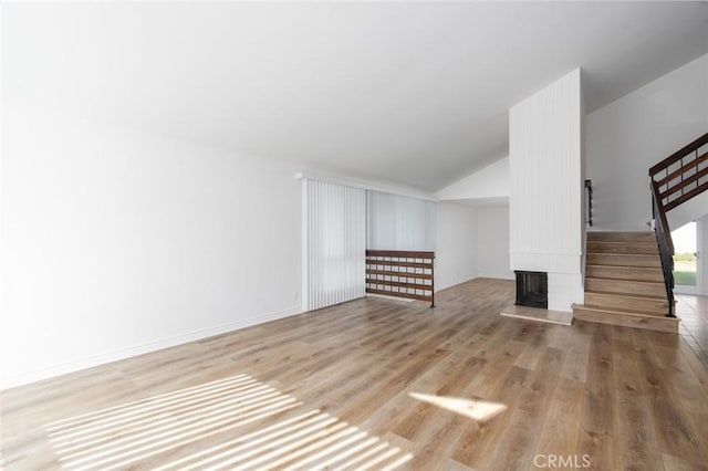 unfurnished living room featuring stairway, a multi sided fireplace, vaulted ceiling, wood finished floors, and baseboards