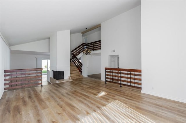 interior space with visible vents, stairway, high vaulted ceiling, light wood-type flooring, and baseboards