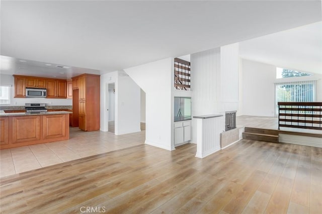 kitchen featuring brown cabinets, light wood-type flooring, stainless steel appliances, and open floor plan