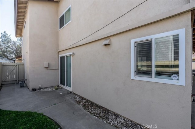 view of property exterior featuring a patio area, fence, and stucco siding