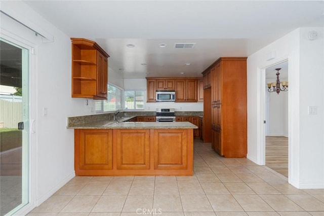 kitchen featuring visible vents, appliances with stainless steel finishes, brown cabinetry, a sink, and a peninsula