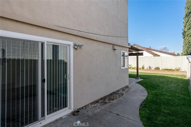 view of side of property with stucco siding, fence, and a yard