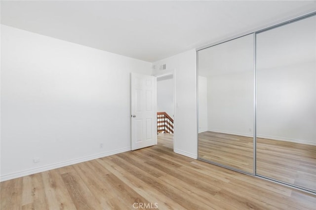 unfurnished bedroom featuring a closet, light wood-type flooring, and baseboards