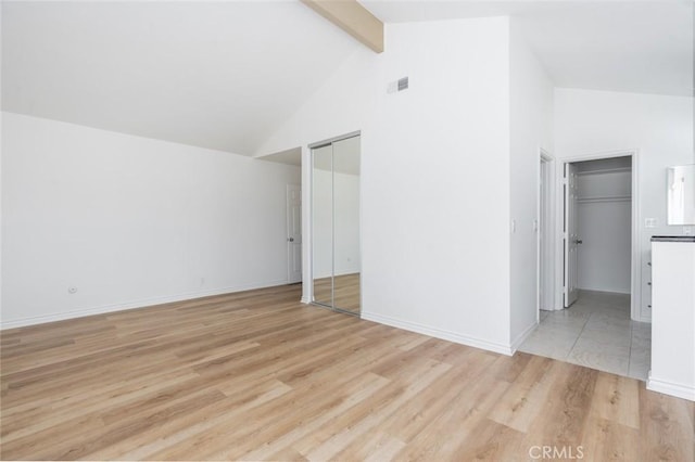 interior space with beam ceiling, visible vents, high vaulted ceiling, light wood-type flooring, and baseboards