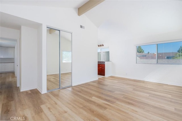 unfurnished bedroom featuring light wood-style floors, visible vents, beamed ceiling, and multiple windows