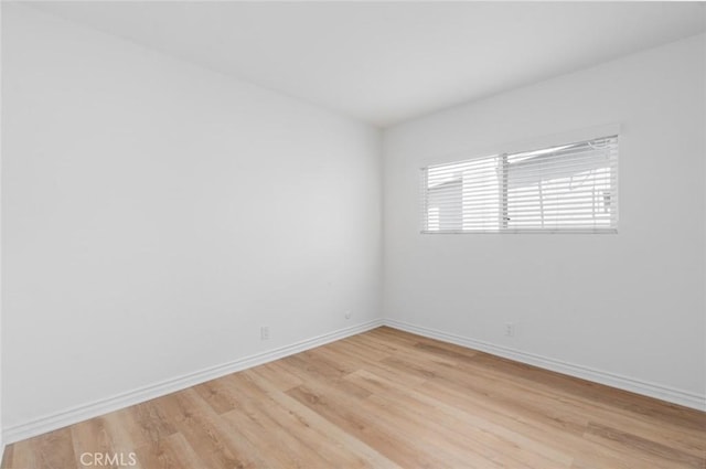 unfurnished room with baseboards and light wood-style floors