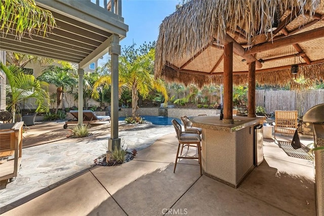 view of patio / terrace featuring fence, outdoor dry bar, and a gazebo