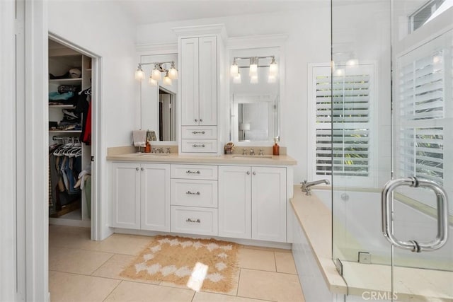 full bathroom featuring a sink, tile patterned flooring, a spacious closet, a shower stall, and a bath