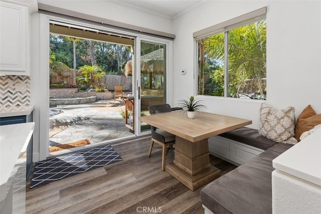 interior space with plenty of natural light, crown molding, breakfast area, and dark wood-type flooring