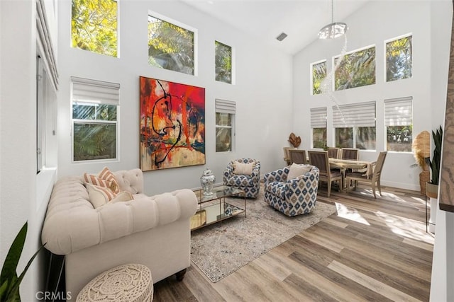 living area with high vaulted ceiling, wood finished floors, and visible vents