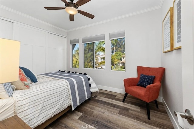 bedroom featuring crown molding, a closet, dark wood-type flooring, a ceiling fan, and baseboards