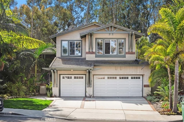 view of front of property with an attached garage, a tiled roof, concrete driveway, and stucco siding