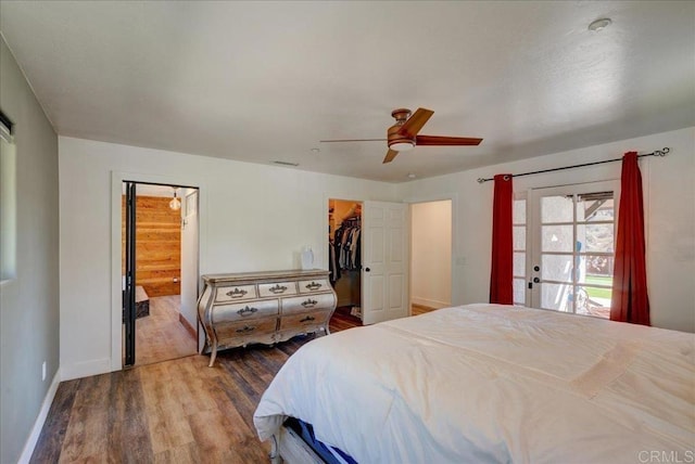 bedroom with visible vents, a closet, baseboards, dark wood-type flooring, and a walk in closet