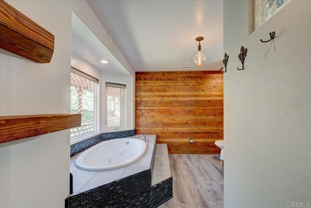 bathroom with wooden walls, a jetted tub, and wood finished floors