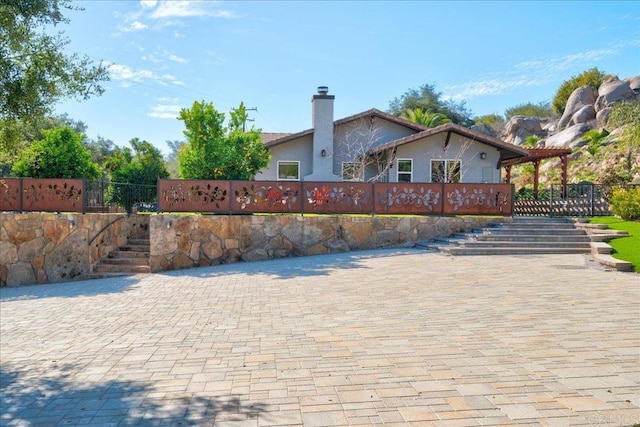 exterior space featuring fence, stairway, stucco siding, and a chimney