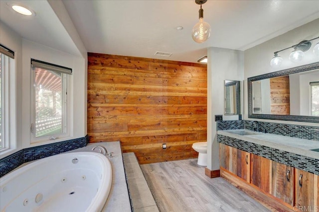 bathroom featuring wood walls, a wealth of natural light, visible vents, and a jetted tub