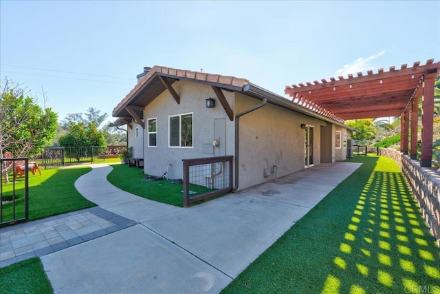 view of side of home featuring a patio, stucco siding, a lawn, a pergola, and fence